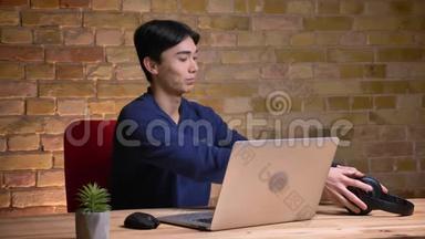 年轻迷人的韩国男学生戴上耳机，在笔记本电脑上打视频电话的特写照片